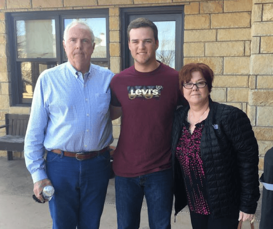 son with grandparents in front of brick building